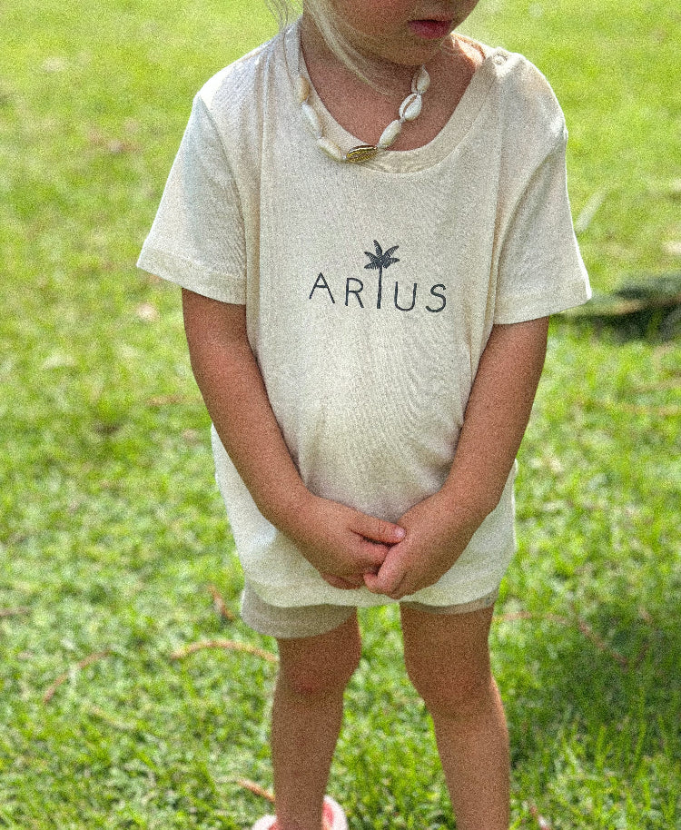 Child wearing Arius Baby Chiller Organic Cotton T-Shirt in natural with palm tree print. 