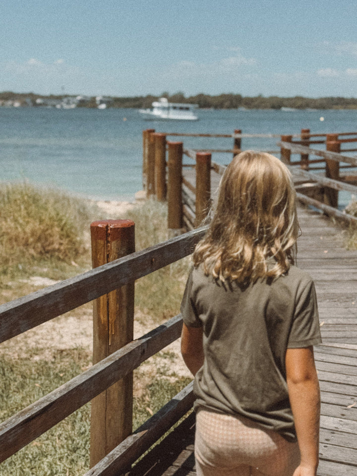 Khaki coloured organic cotton kids t-shirt on beach boardwalk in Australia