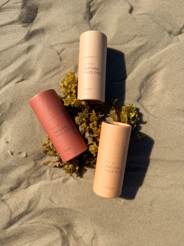 Three shades of natural face zinc laying on seaweed atop of sand at beach