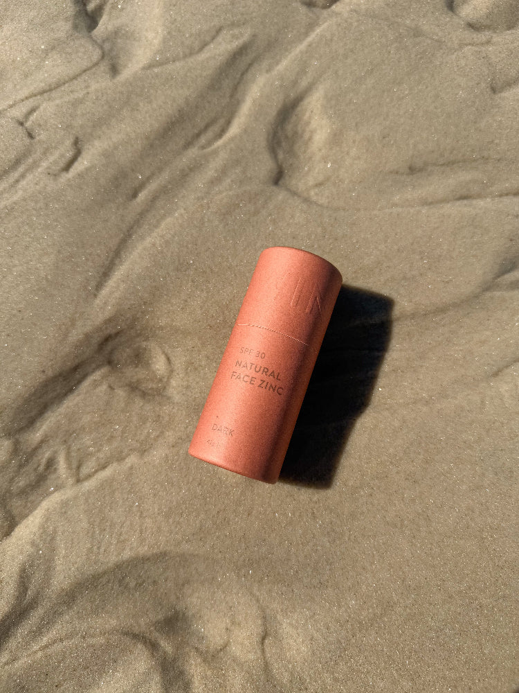 SPF 30 natural face zinc stick in dark shade laying on sand at beach