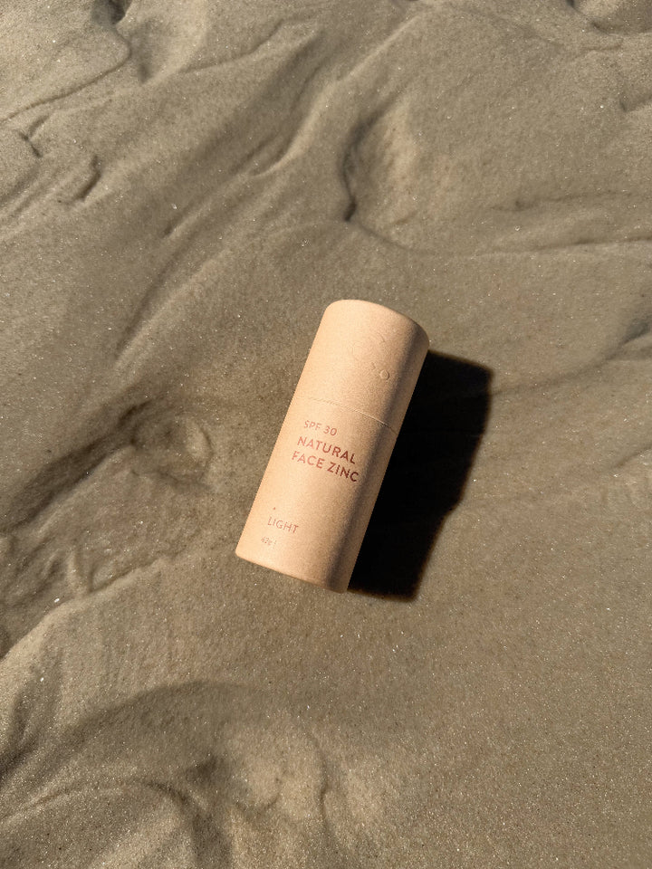 SPF 30 natural face zinc in light skin shade laying on sand