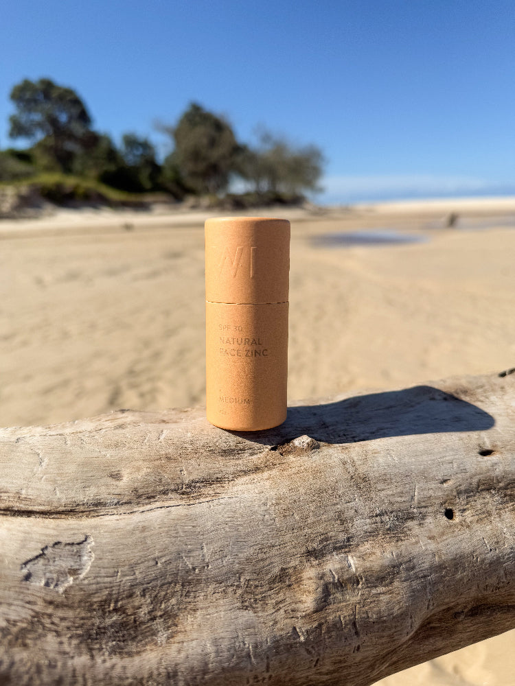 Winki Zinc SPF 30 natural face zinc in medium shade on driftwood at beach