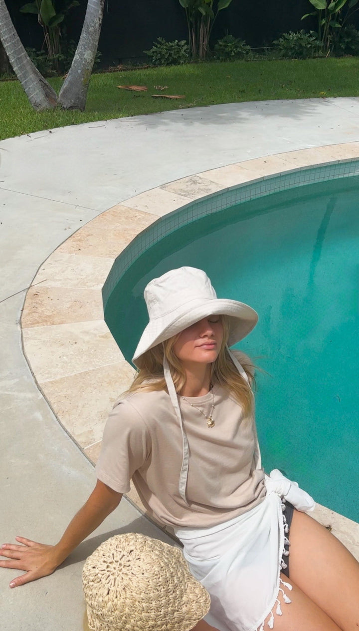 Woman sitting poolside wearing Arius The Vera versatile t-shirt made from Good Earth Cotton in Australia. 