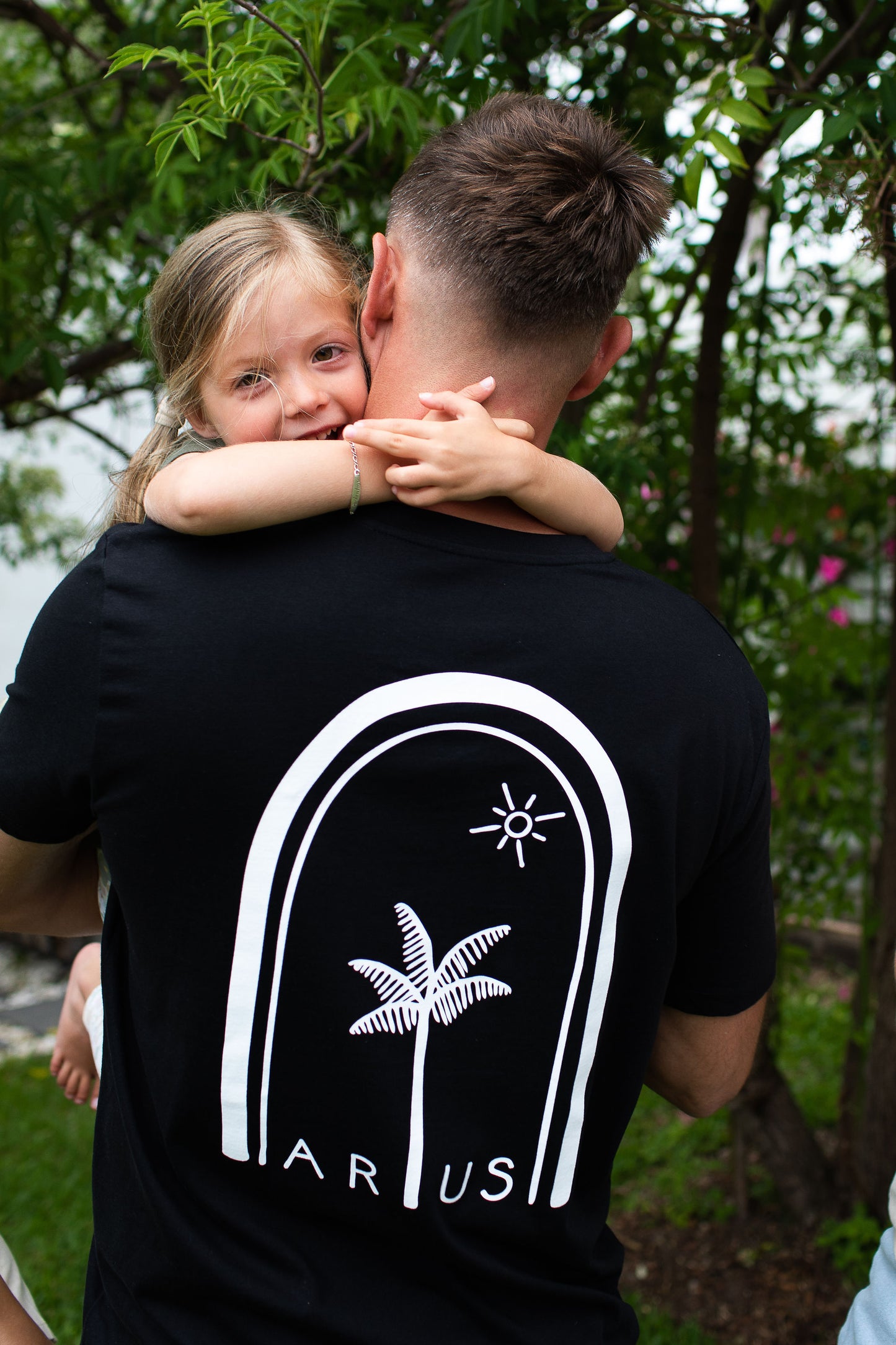 Dad and daughter wearing ethical organic cotton t-shirts with palm tree back