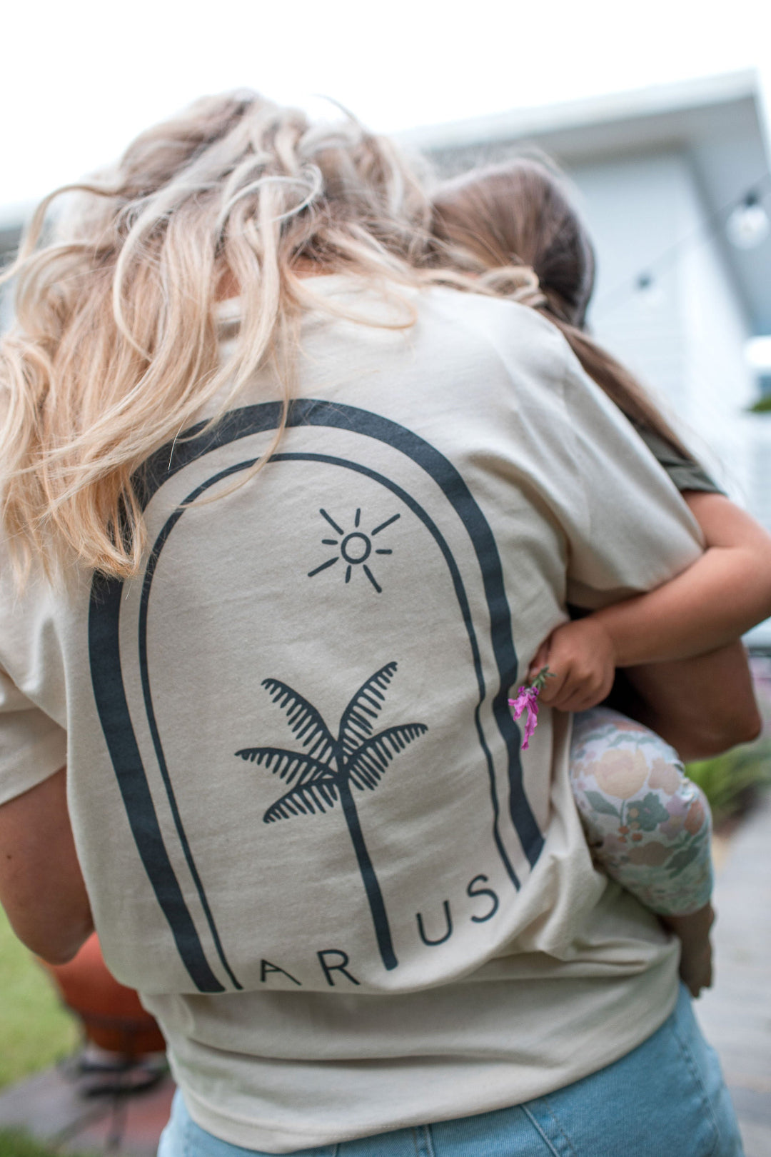 Woman wearing organic cotton natural t-shirt in natural with large palm tree logo on back. 
