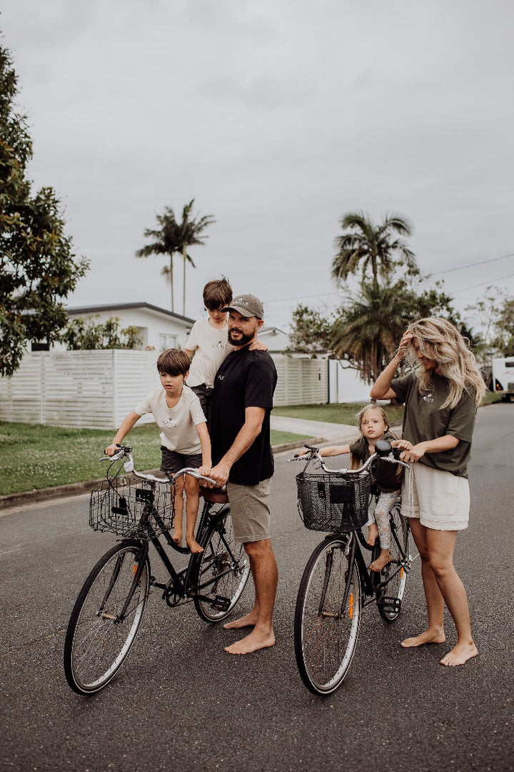 Family on bikes wearing matching organic cotton Arius t-shirts in black, khaki and natural. 