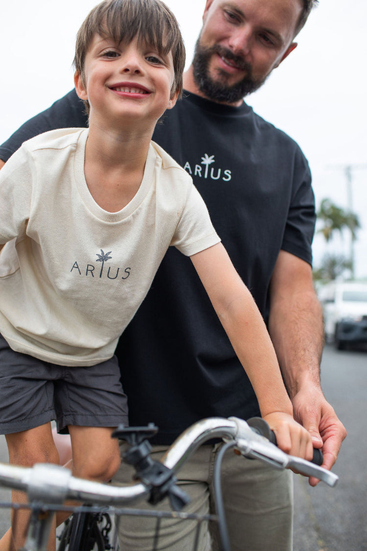 Dad pushing kid on bike both wearing matching organic cotton t-shirt
