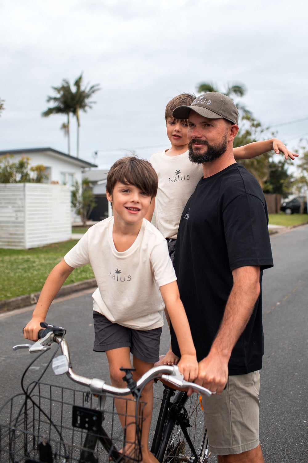 Dad with two sons on bike wearing Arius organic cotton cap and Arius organic cotton t-shirts.